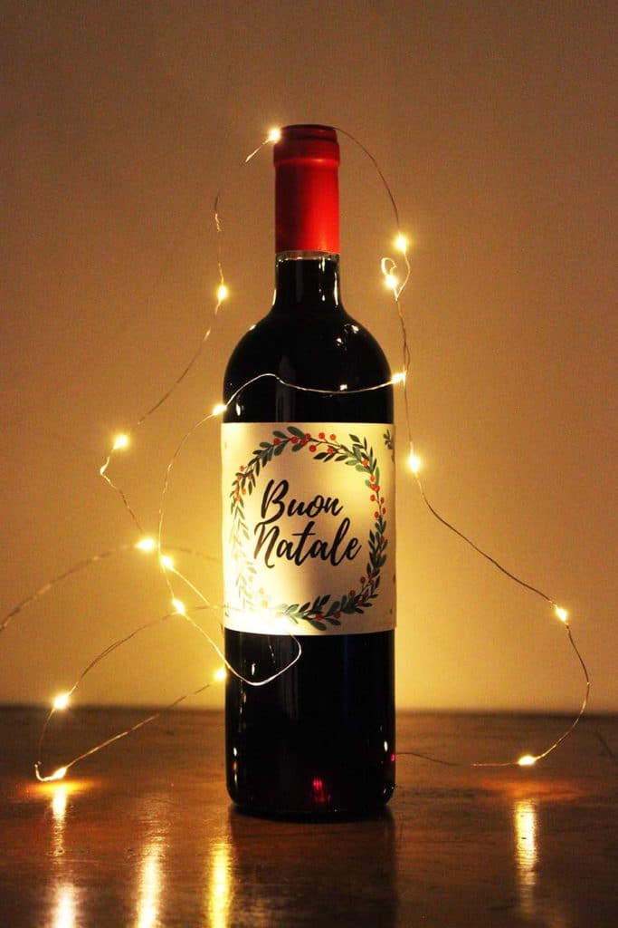 Bottiglia di vino con etichetta a tema natalizio e decorazione con lucine delle feste